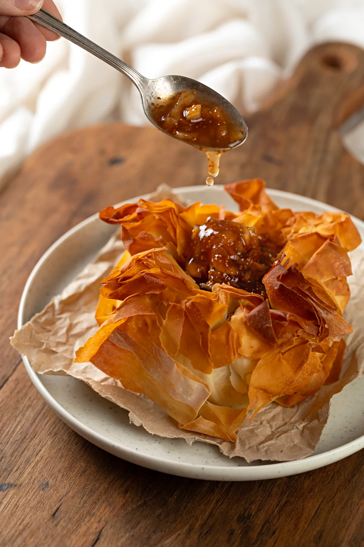 Colher despejando caramelo de figos sobre brie assado em massa phyllo