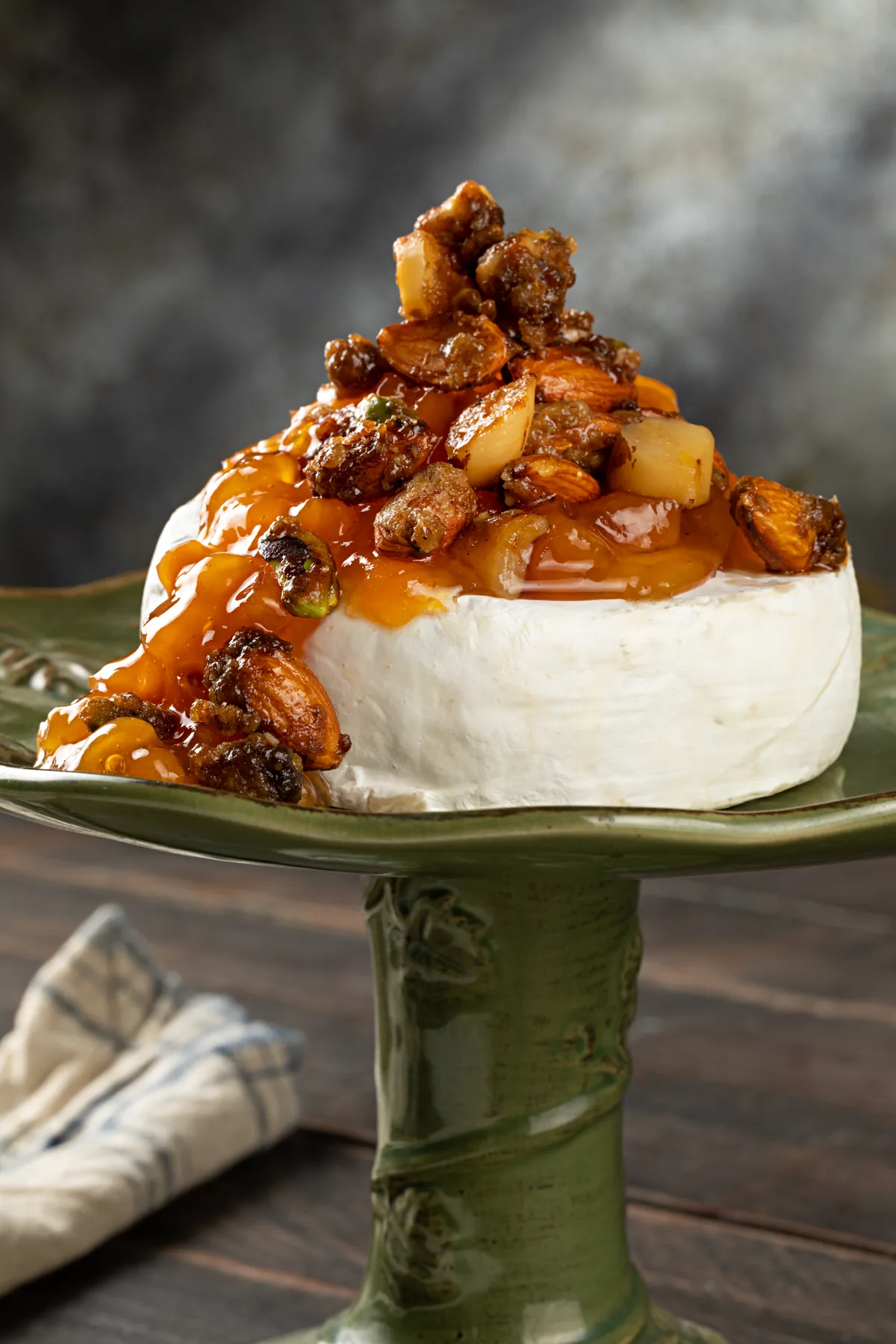 Camembert mineiro inteiro sobre prato verde, coberto de compota de damasco e nuts caramelizados