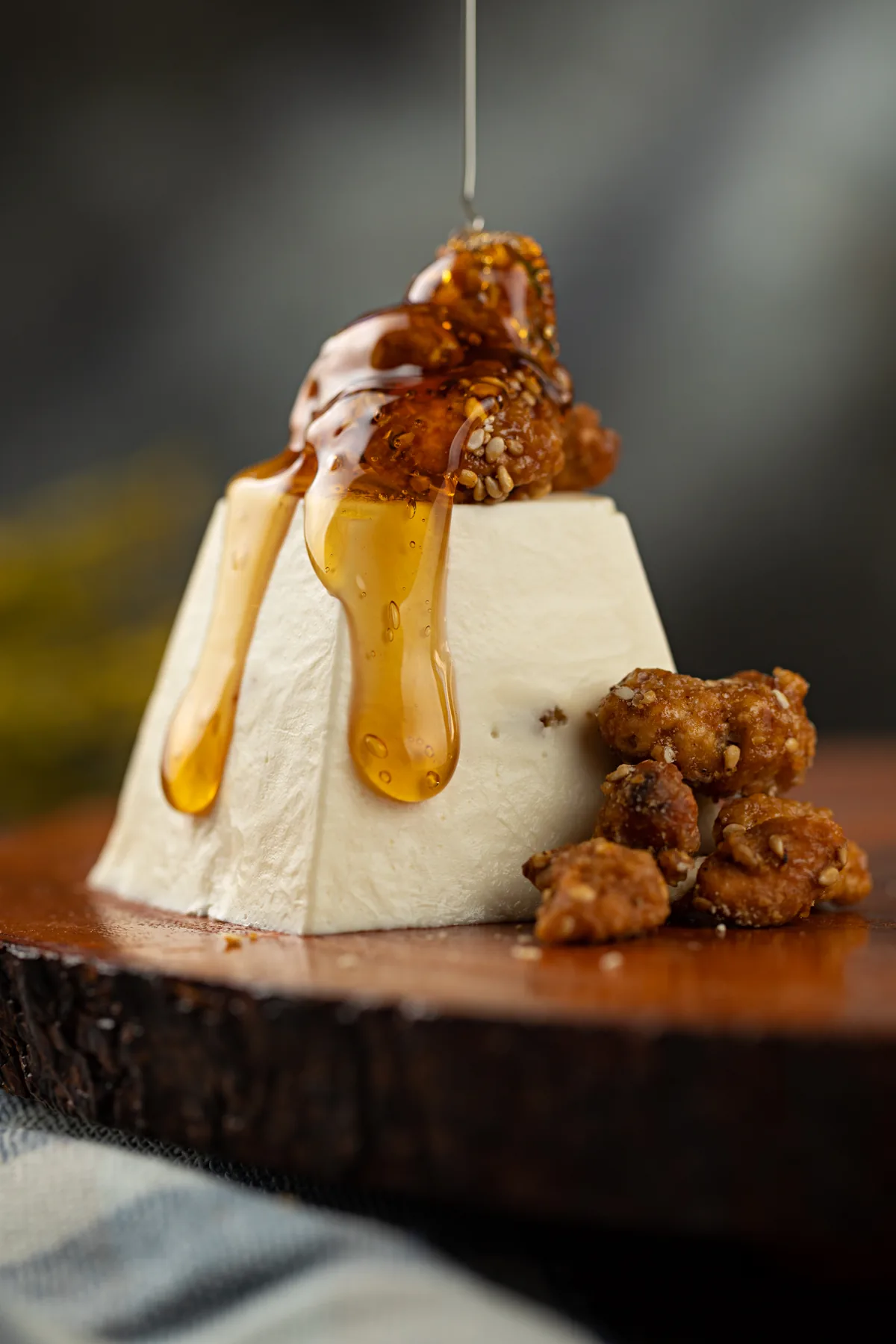 Mousse de chévre em formato de cone, regada com mel e cercada de castanhas caramelizadas
