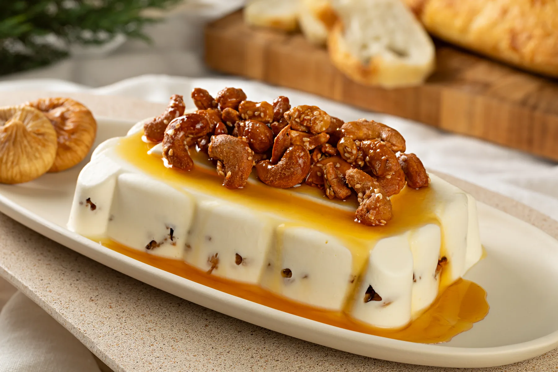 Terrine de chévre retangular em travessa branca, com mel e castanhas caramelizadas por cima